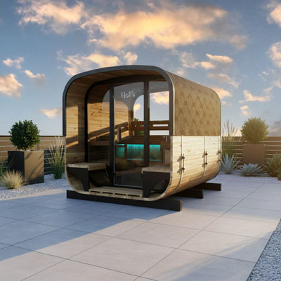 A modern outdoor sauna cabin (Holls Hestia Lounge) with a curved wooden exterior, large glass windows, black trim, situated on a paved patio on a sunny day.